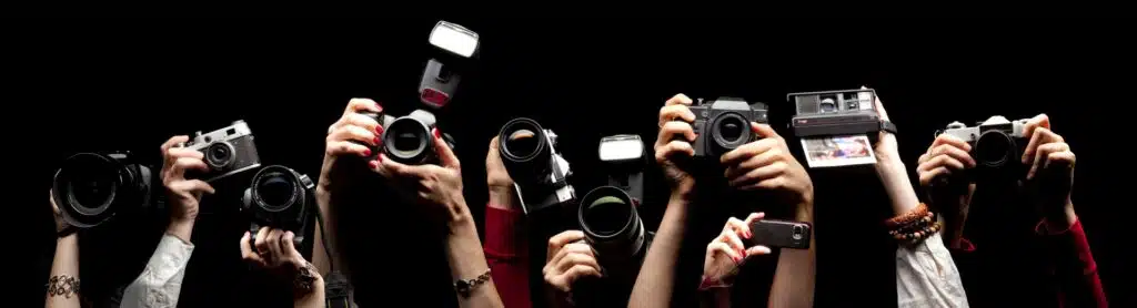 Raised hands holding cameras, representing using HARO for backlinks