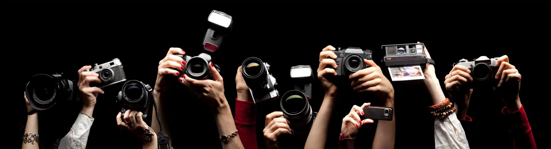 Raised hands holding cameras, representing using HARO for backlinks